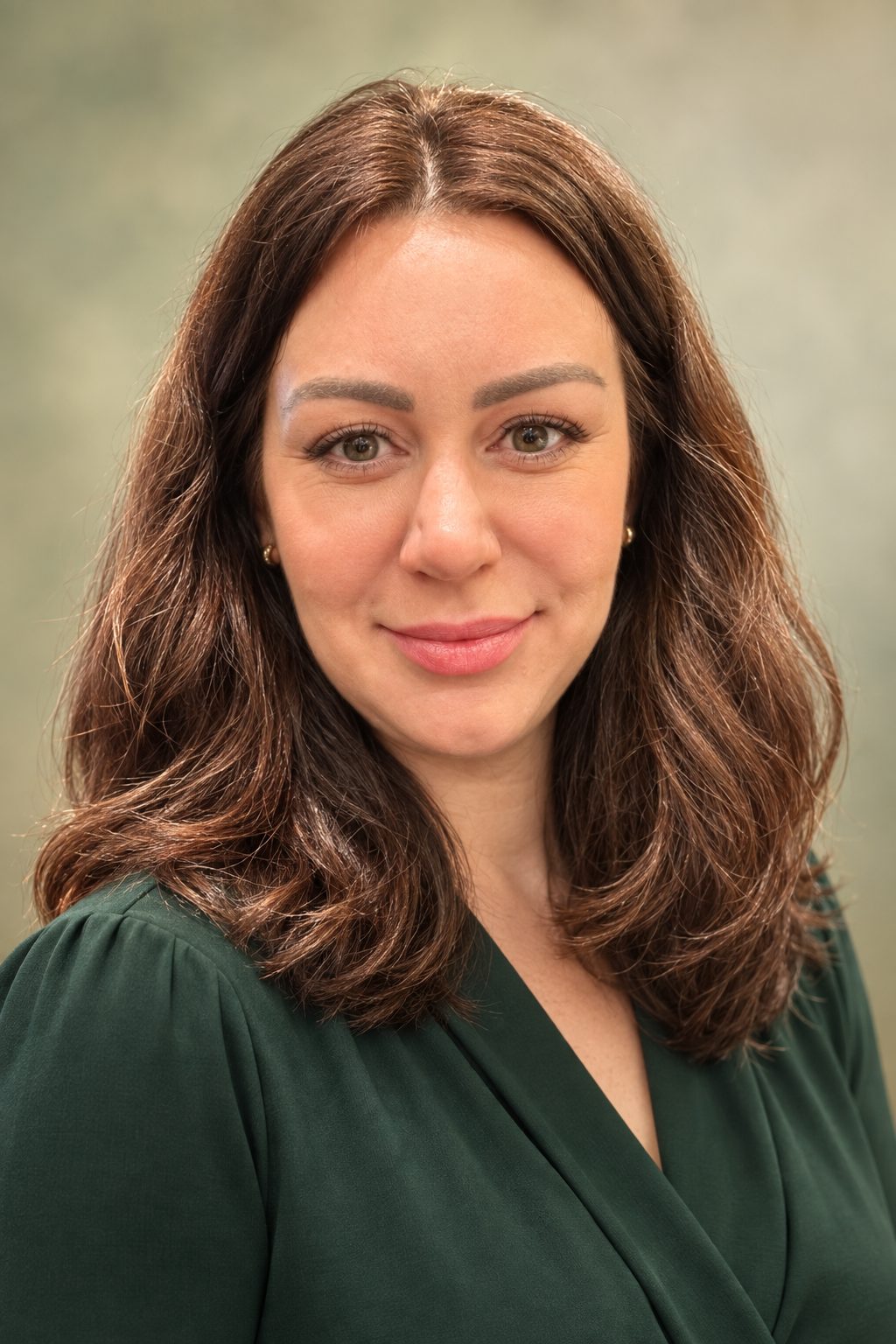 Dr. Irina Sharp, orthodontist, smiling, in a green blouse.